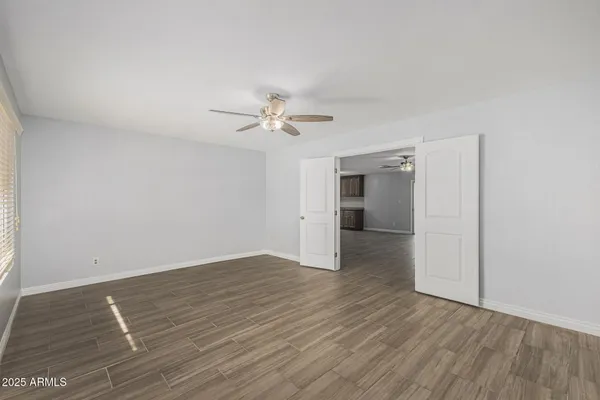 an empty room with wooden floor and ceiling fan