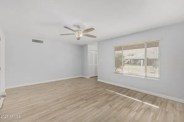 an empty room with wooden floor and windows