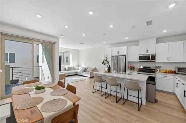 a view of kitchen with stainless steel appliances granite countertop dining table chairs stove microwave and cabinets