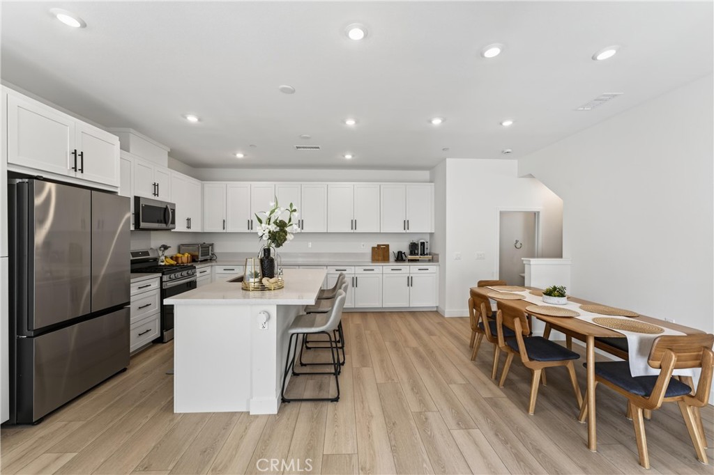 1572 Lima Way, Unit 6 Placentia, CA 92870 - Photo 12 of 36 a kitchen with stainless steel appliances kitchen island granite countertop a refrigerator a stove a sink a dining table and chairs with wooden floor