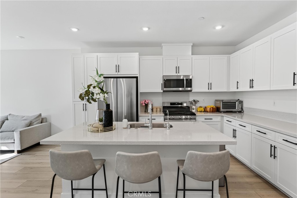 1572 Lima Way, Unit 6 Placentia, CA 92870 - Photo 2 of 35 a kitchen with stainless steel appliances kitchen island granite countertop a dining table chairs refrigerator and sink