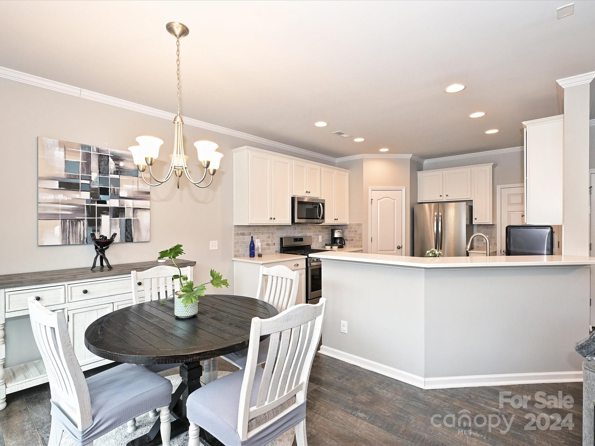 4041 Woodsmill Road Indian Land, SC 29707 - Photo 11 of 36 a kitchen with stainless steel appliances kitchen island granite countertop a dining table chairs and white cabinets