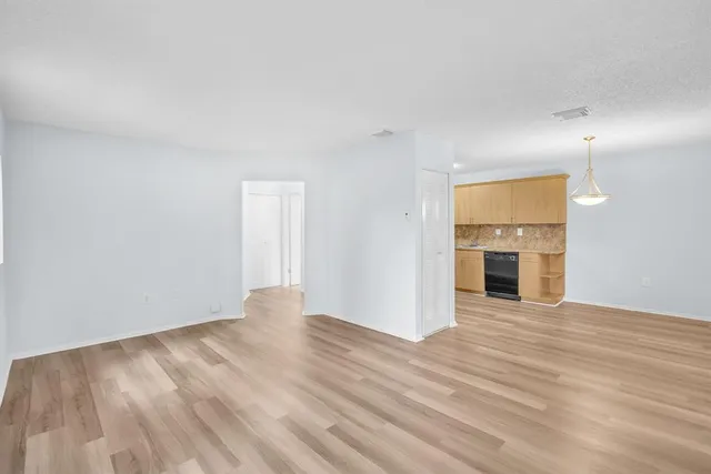 an empty room with wooden floor fireplace and windows