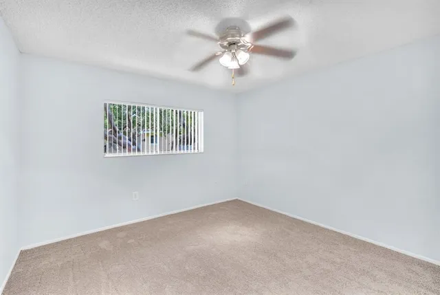 an empty room with windows and fan