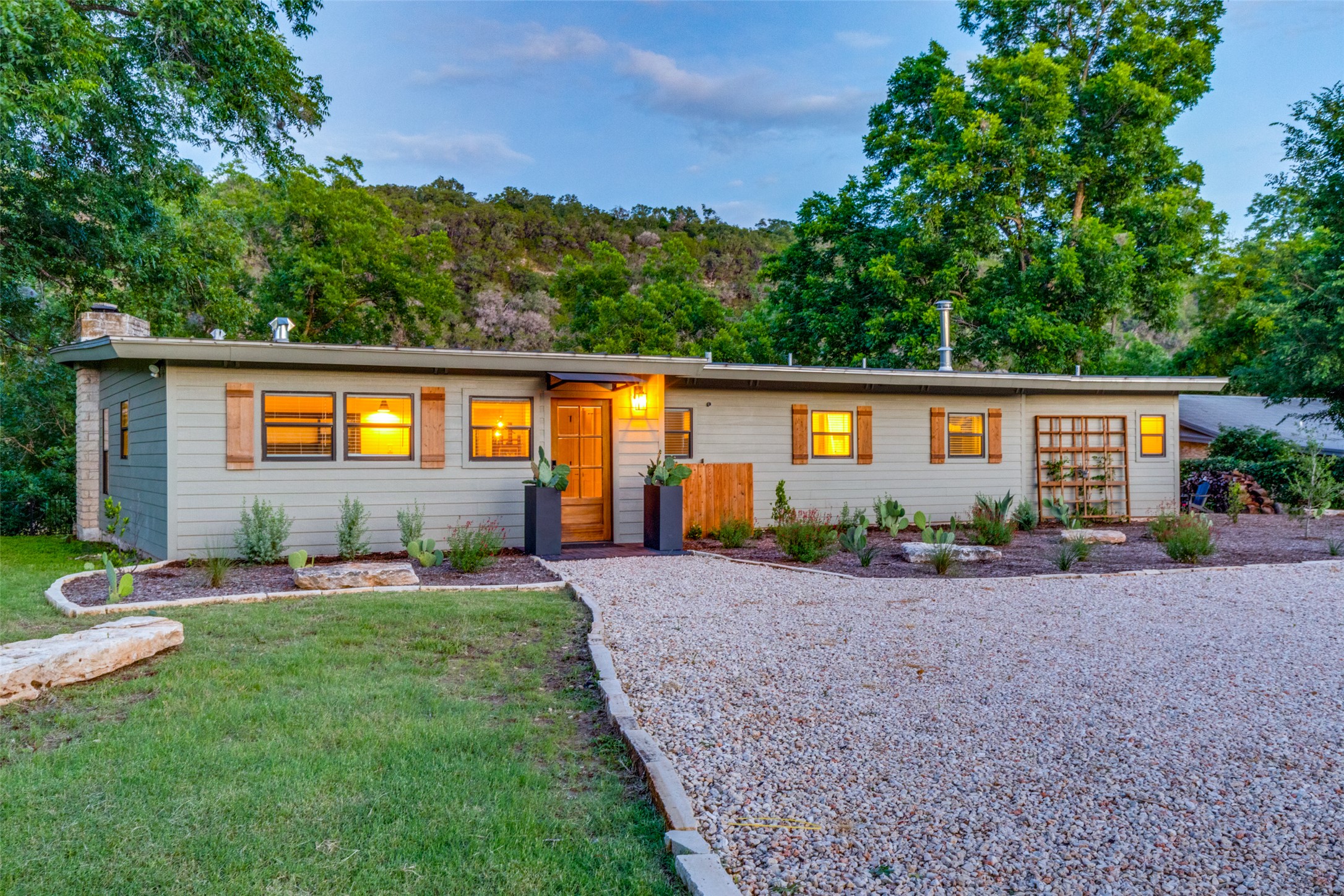 303 Lago Verde Road Austin, TX 78734 - Photo 1 of 39 A charming exterior with a gravel driveway, wood shutters, and well-maintained landscaping.