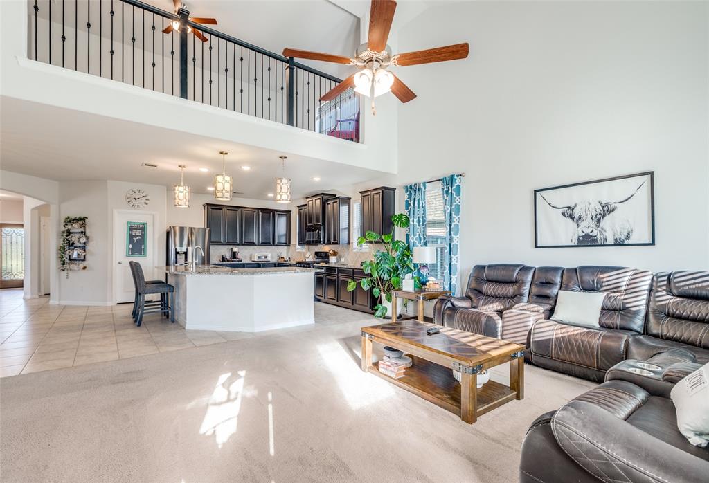 4542 Kipling Avenue Aubrey, TX 76227 - Photo 11 of 36 Living area with a ceiling fan, light colored carpet, healthy amount of natural light, and a high ceiling