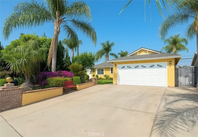 a view of a house with a yard and palm trees