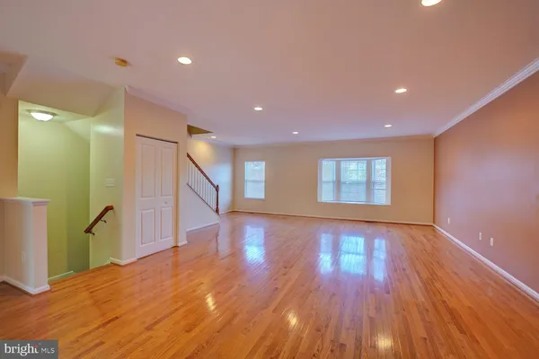 a view of an empty room with wooden floor and a fireplace