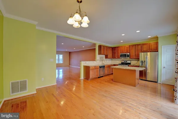 a view of an empty room with wooden floor and a bathroom