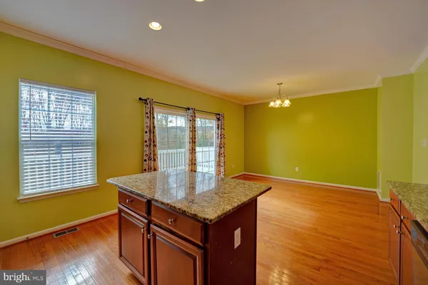 a kitchen with stainless steel appliances granite countertop a stove top oven a refrigerator a sink and dishwasher with wooden floor