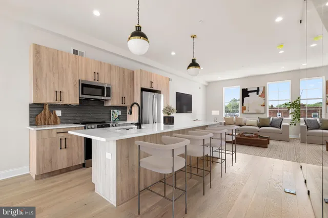 a living room with stainless steel appliances kitchen island a white cabinets and couches