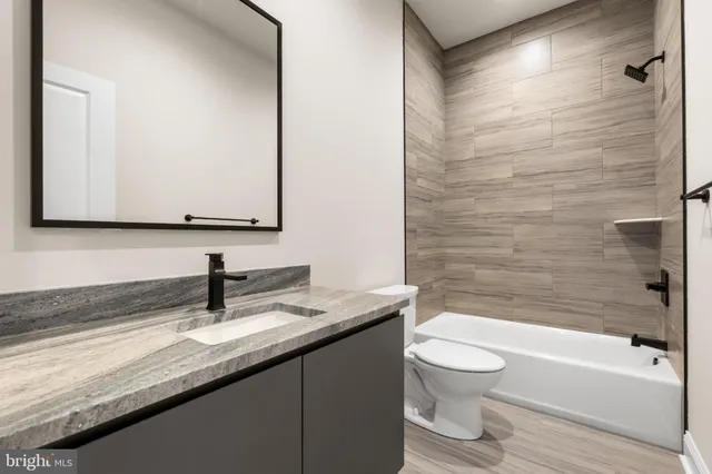 a bathroom with a granite countertop sink a toilet and bathtub