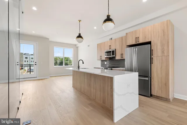 a kitchen with stainless steel appliances a refrigerator a stove a sink a center island and a window