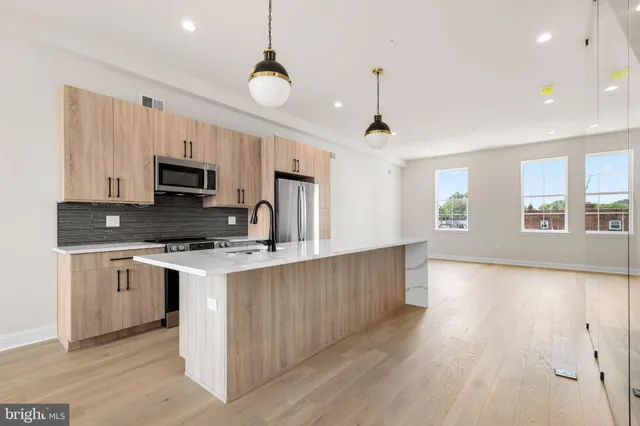 a kitchen with kitchen island granite countertop a stove top oven a sink a counter space and cabinets
