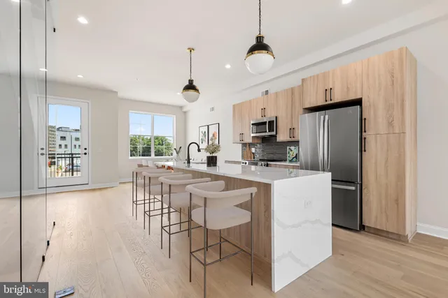 a kitchen with stainless steel appliances a dining table chairs stove and refrigerator