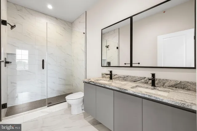 a bathroom with a granite countertop sink a toilet and shower