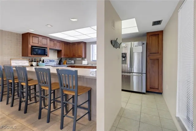 a kitchen with stainless steel appliances a refrigerator a stove a sink a dining table and chairs