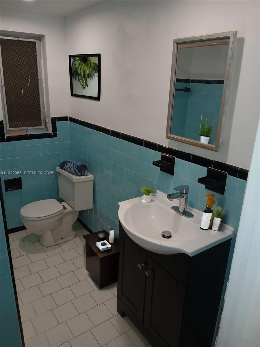 7300 Byron Avenue, Unit 8 Miami Beach, FL 33141 - Photo 5 of 9 a bathroom with a toilet sink and mirror