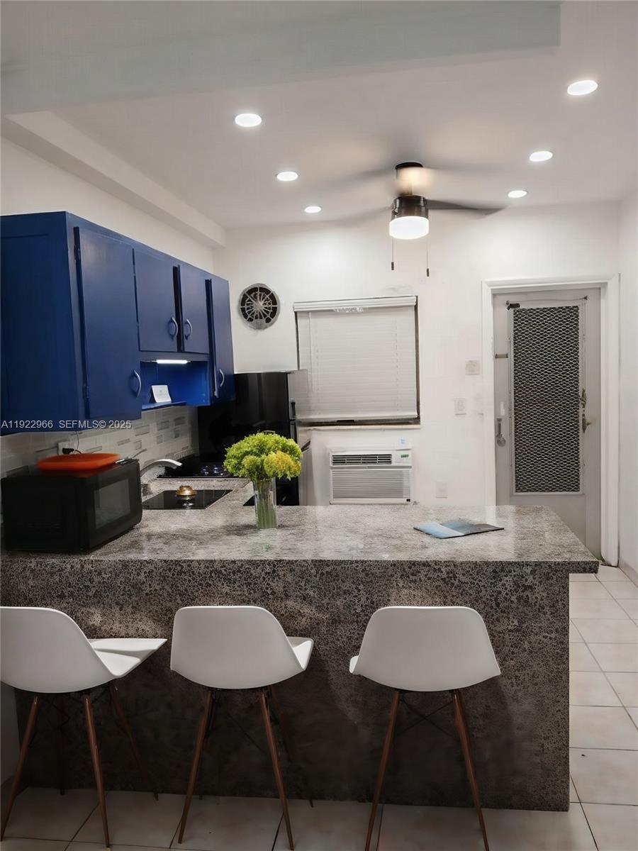 7300 Byron Avenue, Unit 8 Miami Beach, FL 33141 - Photo 6 of 9 a kitchen with stainless steel appliances granite countertop a stove a sink a microwave a refrigerator and chairs