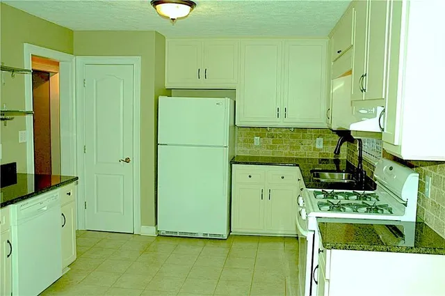 a kitchen with a refrigerator a stove a washer dryer and cabinets