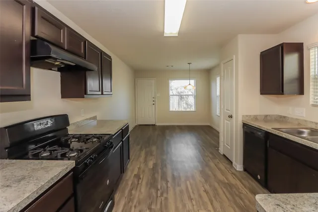 a kitchen with granite countertop a stove wooden floor and a sink