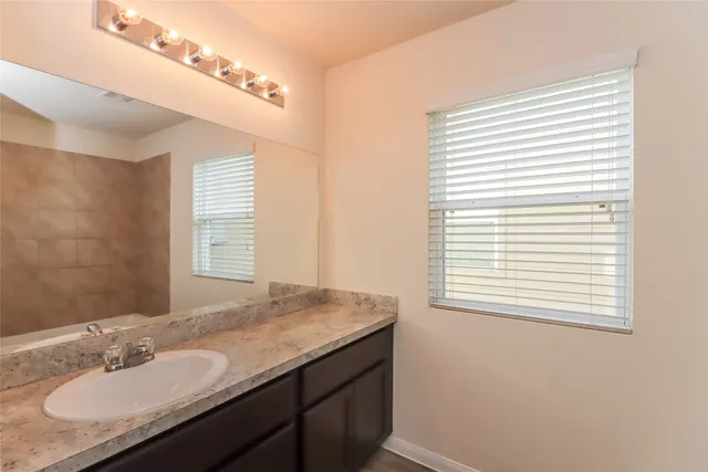 a bathroom with a granite countertop sink and a mirror