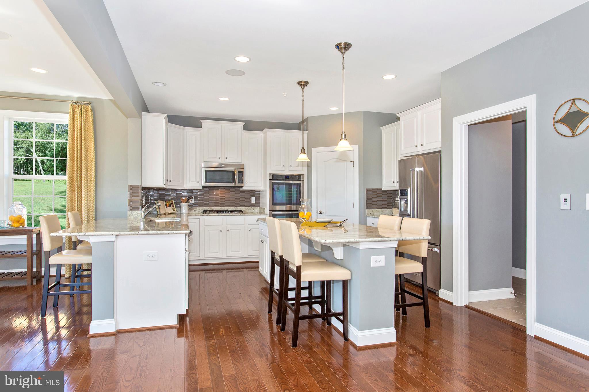 2112 Gable Drive Jessup, MD 20794 - Photo 15 of 27 a kitchen with stainless steel appliances granite countertop a refrigerator a stove top oven a dining table and chairs with wooden floor