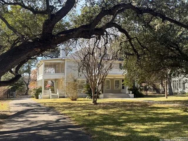 a front view of a house with a large tree