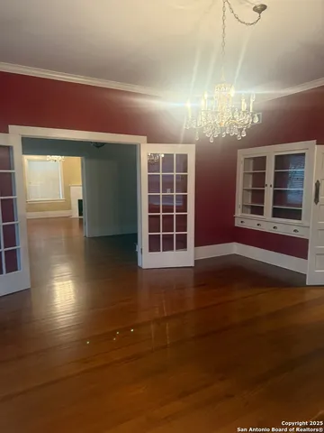 a view of an empty room with wooden floor and windows