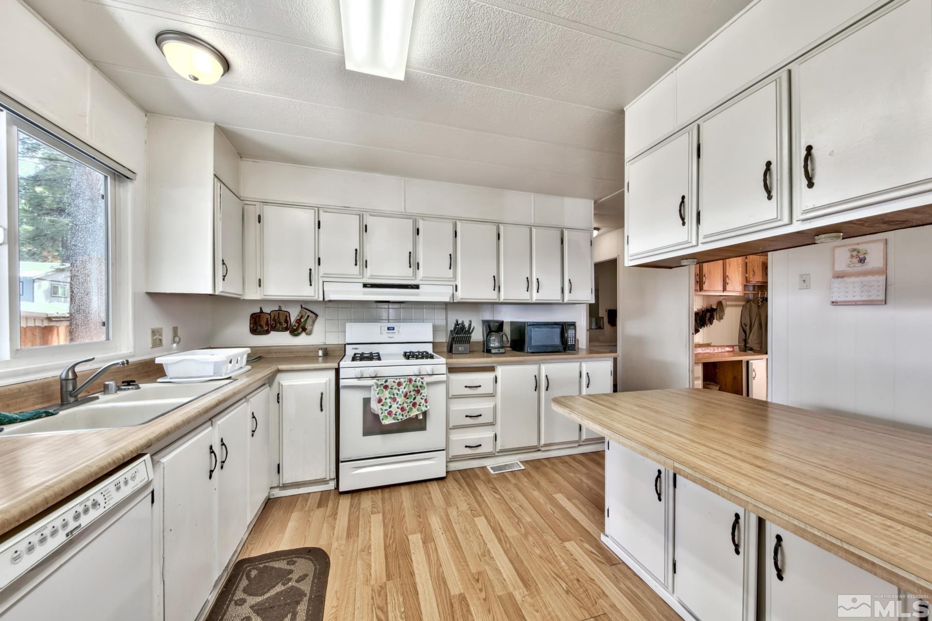 167 Crescent Drive Stateline, NV 89449 - Photo 12 of 23 a kitchen with white cabinets stainless steel appliances a sink and wooden floor