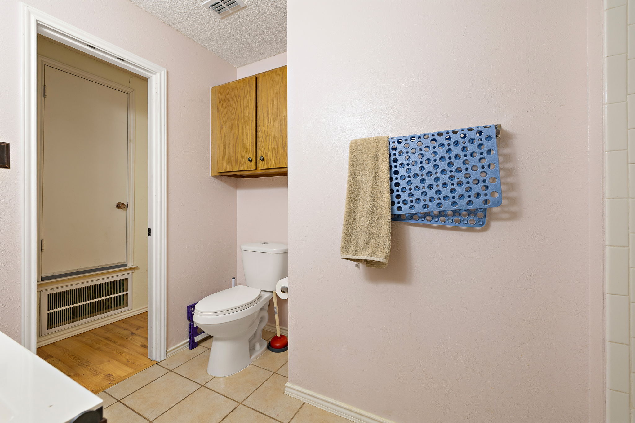 11709 Rotherham Drive Austin, TX 78753 - Photo 21 of 25 Functional bathroom featuring light-colored walls and classic tiled flooring, with wood cabinetry above the toilet.