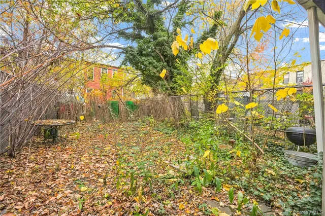 a backyard of a house with table and chairs under an umbrella