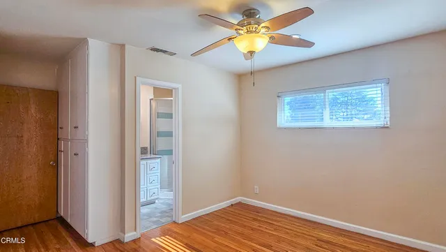 a view of an empty room with window and wooden floor