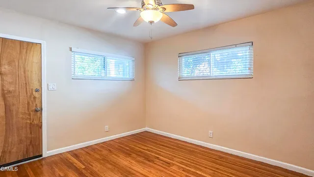 a view of an empty room with wooden floor and a window