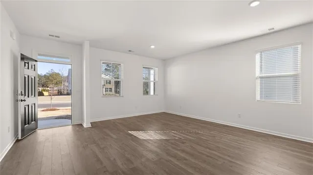 an empty room with wooden floor and windows