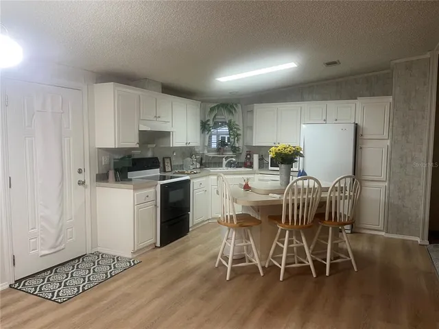 a kitchen with a table chairs refrigerator and microwave
