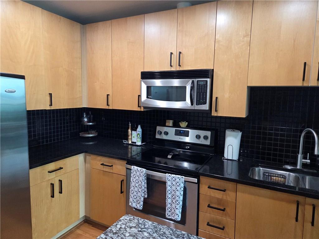 250 Pharr Road Northeast, Unit 1816 Atlanta, GA 30305 - Photo 14 of 36 a kitchen with granite countertop a stove a microwave a sink and cabinets