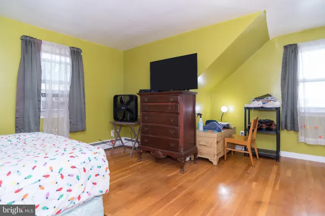 a bedroom with a bed and a dresser with wooden floor