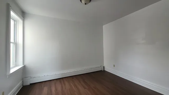 a view of an empty room with wooden floor and window