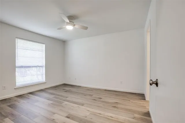 an empty room with wooden floor cabinet and windows