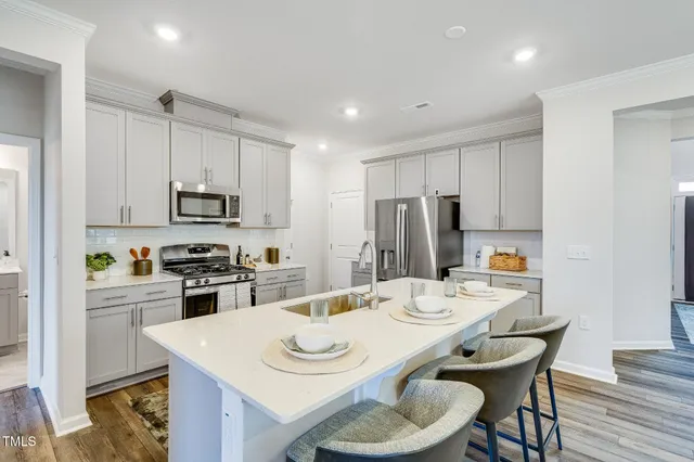 a kitchen with stainless steel appliances granite countertop a kitchen island a stove a table and chairs