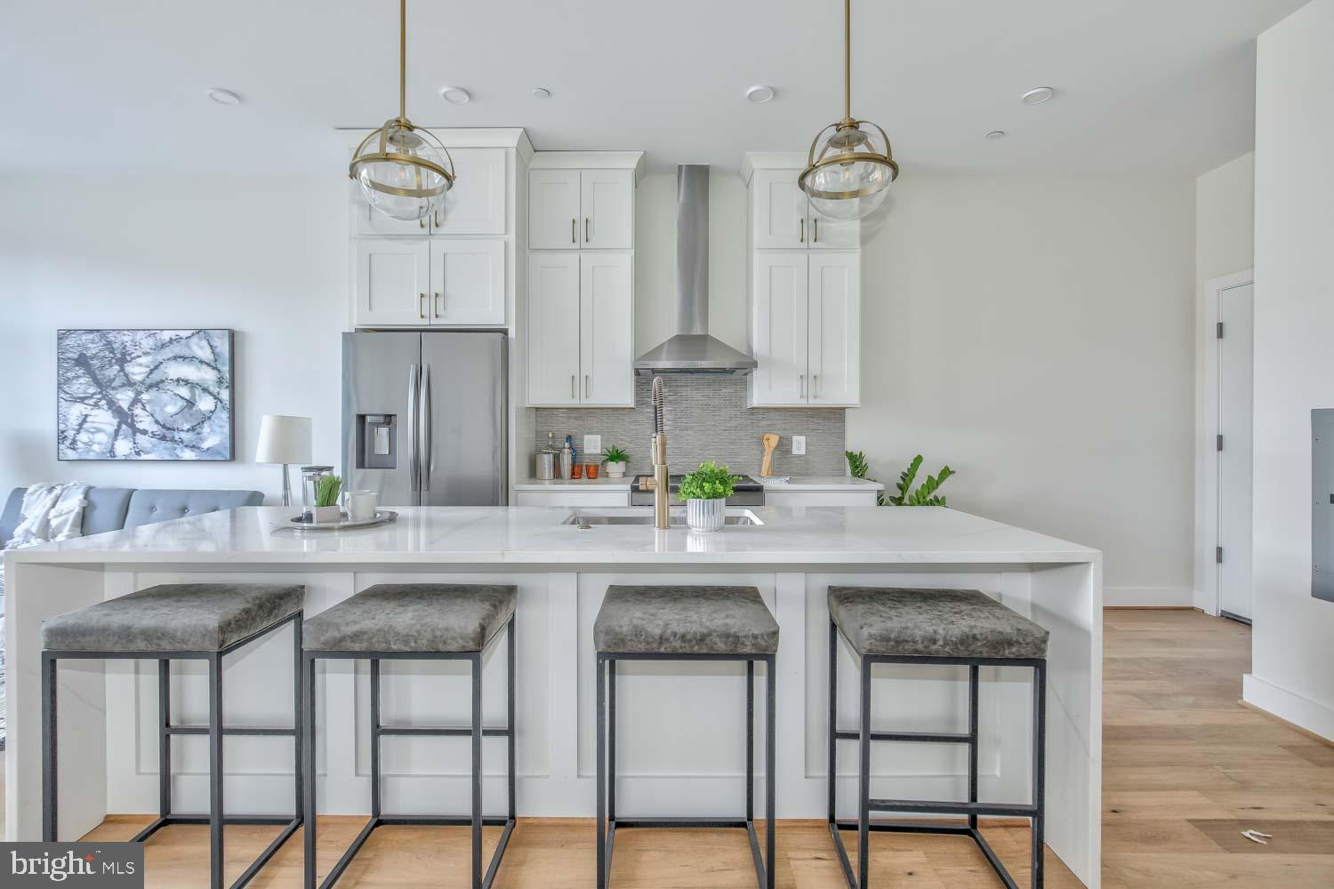 4347 Harrison Street Northwest, Unit 4 Washington, DC 20015 - Photo 8 of 16 a kitchen with stainless steel appliances granite countertop a table chairs in it and wooden floors