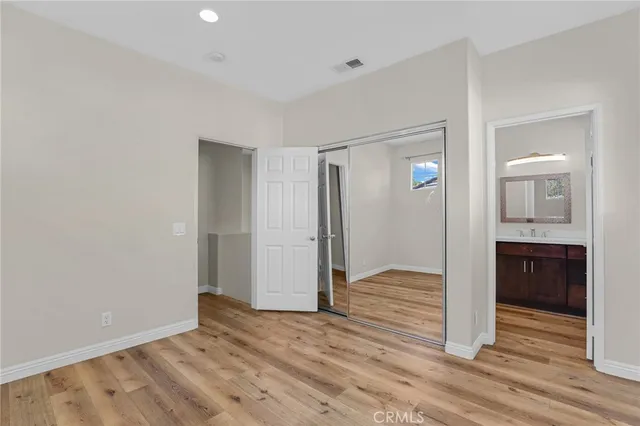 a view of an empty room with wooden floor and a bathroom