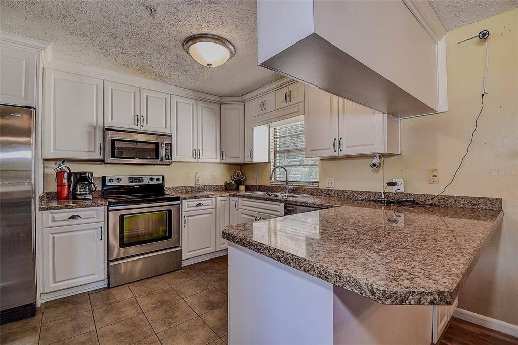 11425 Sun Road Dade City, FL 33525 - Photo 11 of 41 a kitchen with granite countertop a sink stainless steel appliances and white cabinets