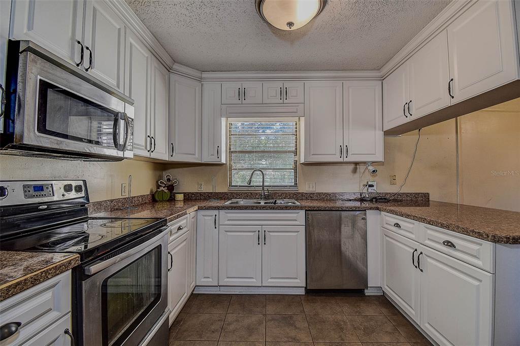 11425 Sun Road Dade City, FL 33525 - Photo 13 of 41 a kitchen with stainless steel appliances granite countertop a stove a sink dishwasher and a microwave oven