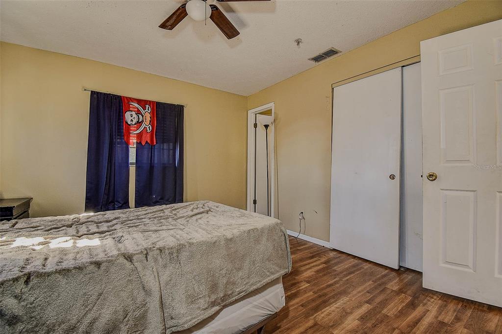 11425 Sun Road Dade City, FL 33525 - Photo 15 of 41 a bedroom with a large bed and wooden floor
