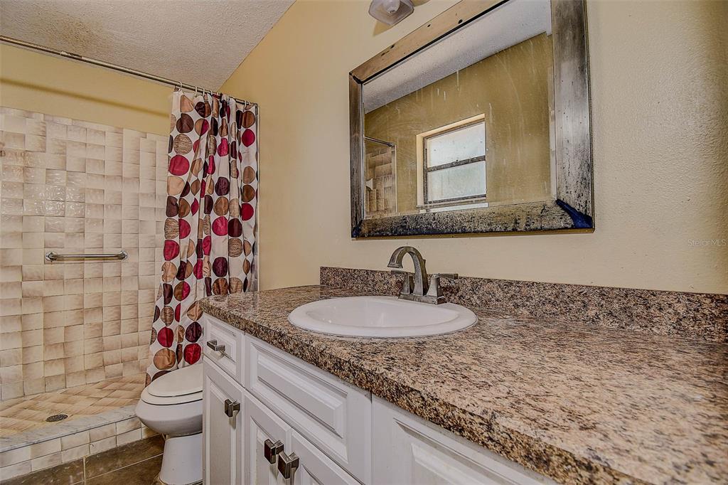 11425 Sun Road Dade City, FL 33525 - Photo 16 of 41 a bathroom with a granite countertop sink mirror vanity and toilet