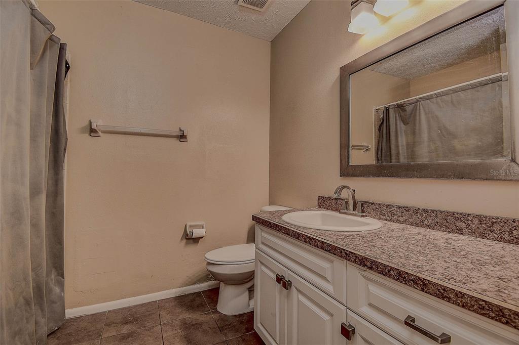 11425 Sun Road Dade City, FL 33525 - Photo 19 of 41 a bathroom with a granite countertop sink toilet and mirror