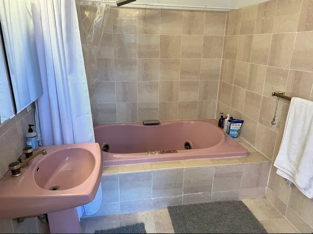 a bathroom with a tub a sink and a mirror