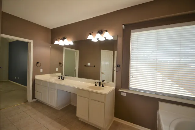 an empty room with chandelier fan and windows